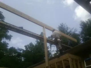 Carpenter setting a ridge beam over a new addition frame — Ice Dam Removal by Roofing Brothers in Grays River