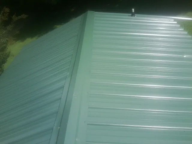 New green metal panels meeting at the ridge of a roof — Flat Roof Repair work by our crew in Grays River