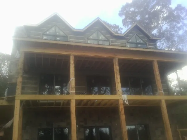 Dormers and porch framing on a large log home under construction — Roof Coating work by our crew in Grays River