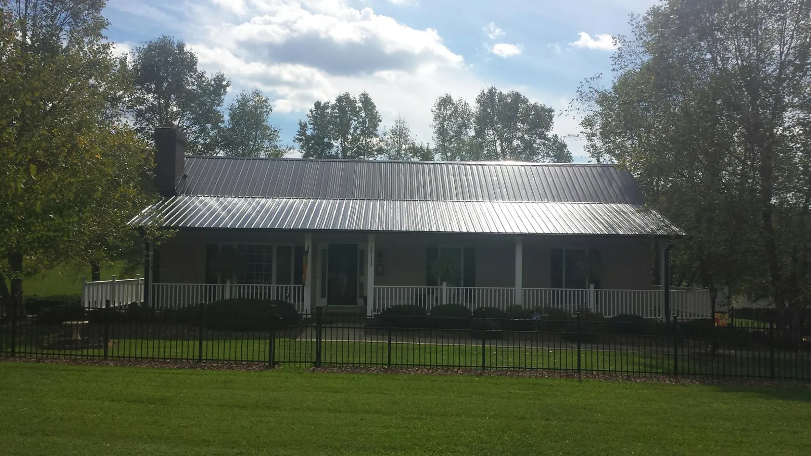 Gray metal roof on a brick ranch with a full width front porch — Gutter Guard Installation work by our crew in Grays River