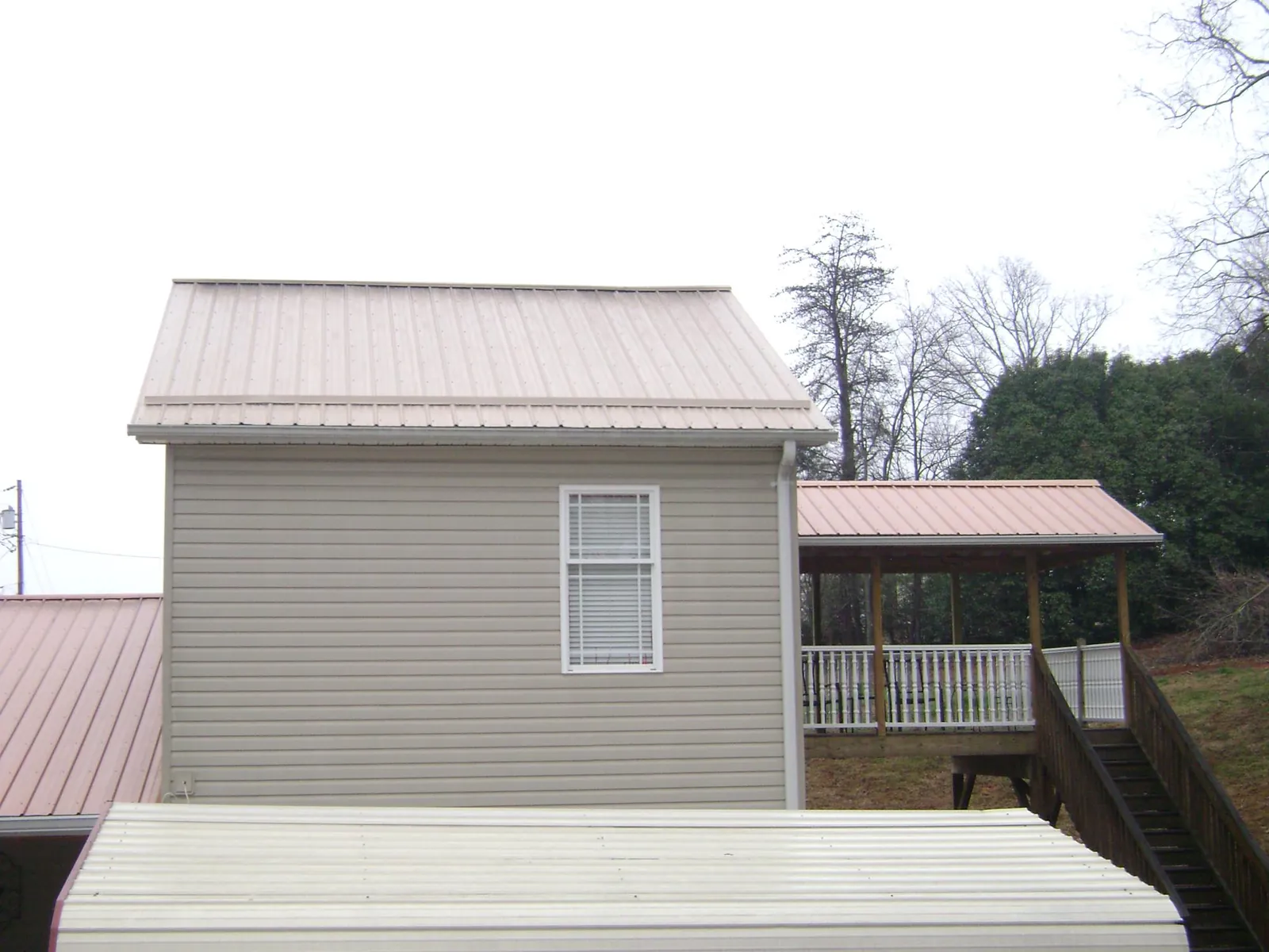 Tan metal roofs on a two story addition and attached porch, from a Roof Replacement job in Grays River
