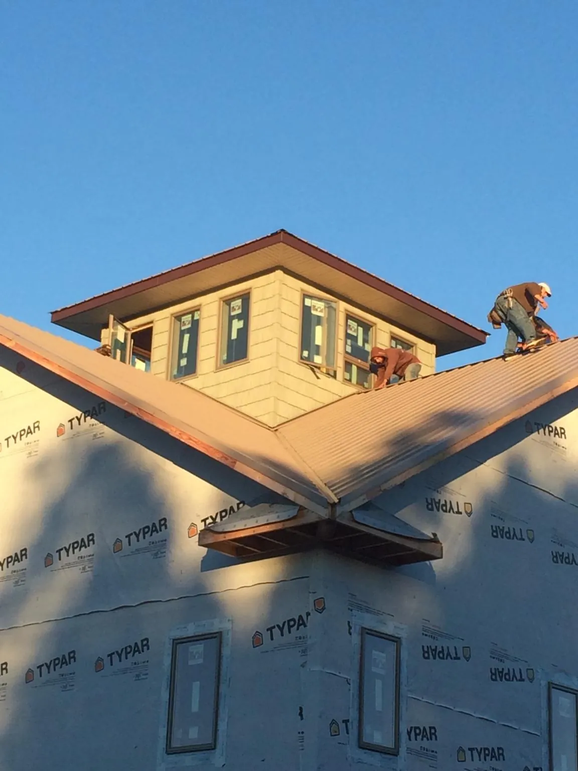 Roofers working around a rooftop cupola on a new metal roof at sunset — Roof Waterproofing in Grays River by Roofing Brothers